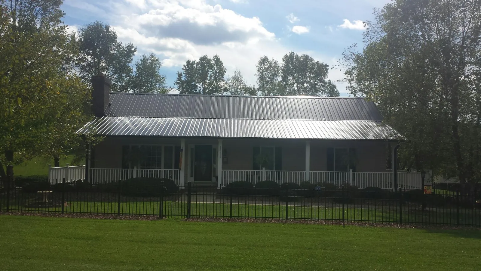 Gray metal roof on a brick ranch with a full width front porch — Gutter Guard Installation work by our crew in Millbrook