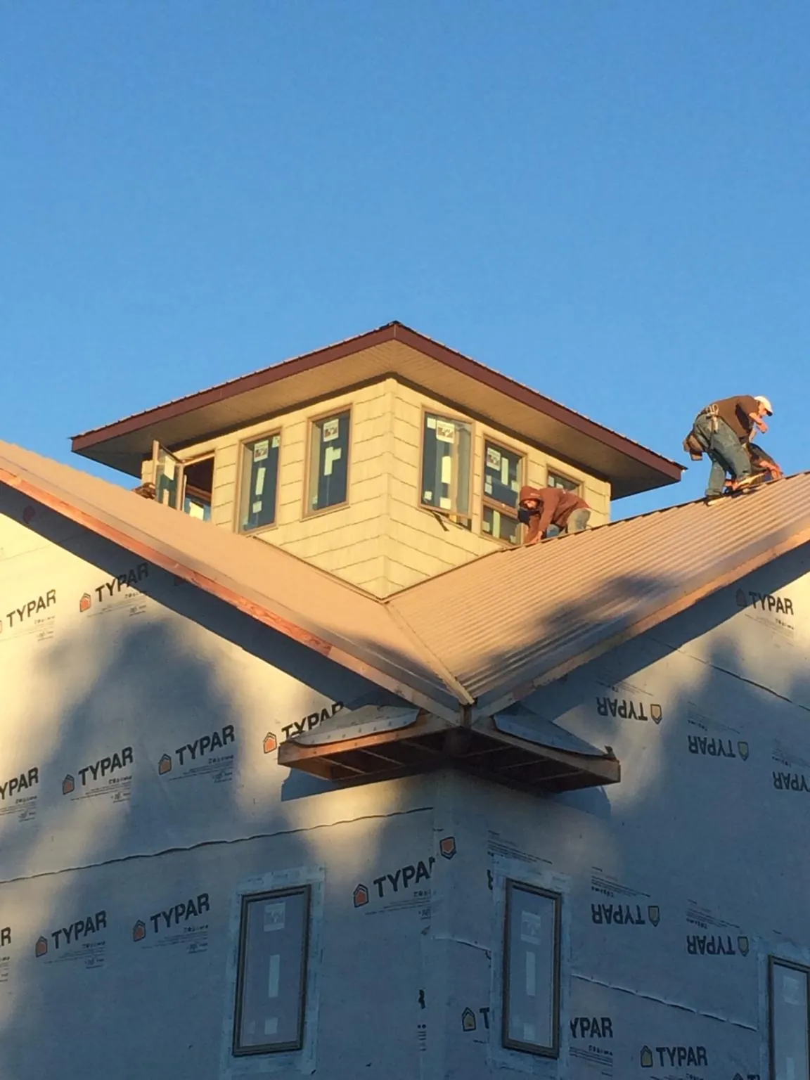 Roofers working around a rooftop cupola on a new metal roof at sunset — Roof Waterproofing in Millbrook by Roofing Brothers